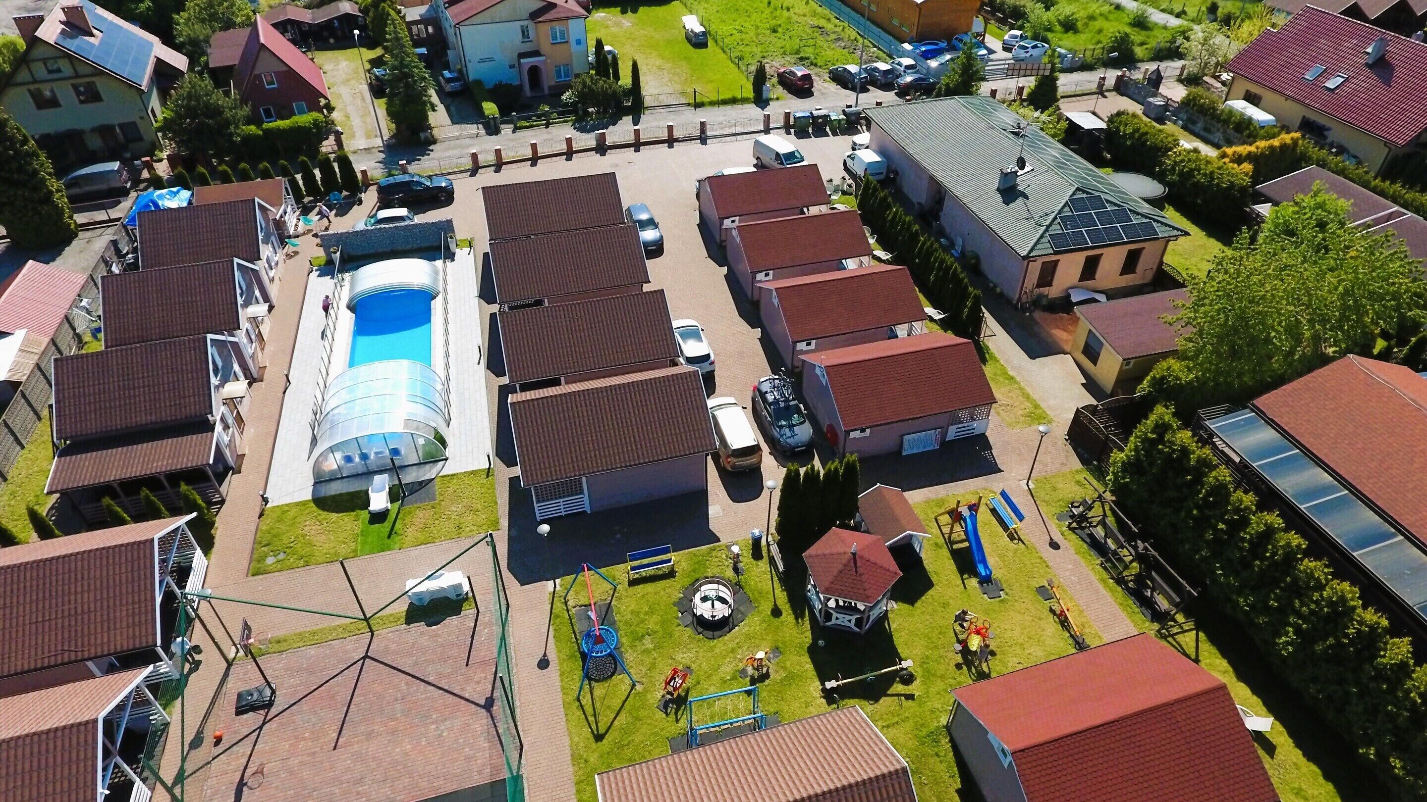 Vue aérienne d’un quartier résidentiel avec des maisons, une piscine et un terrain de jeux.