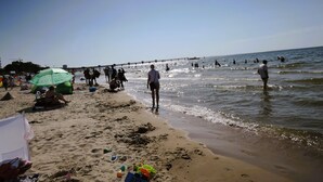 Una playa con gente caminando por la orilla y un muelle que se adentra en el agua.