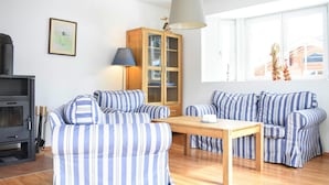 Ein Wohnzimmer mit gestreiften Sofas, einem Holzschrank, einem Tisch und einem Kamin.