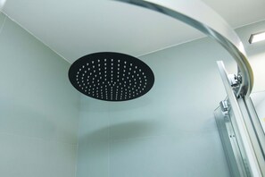 Ducha moderna con un rociador negro circular y un grifo de cromo curvo.