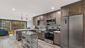 Una cocina moderna con electrodomésticos de acero inoxidable, armarios de madera y una isla central.