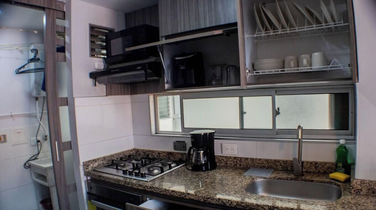 A compact kitchen with a gas stove, a coffee maker, and a sink.