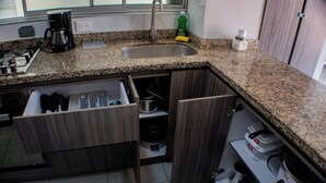 A kitchen with a granite countertop, a sink, a coffee maker, and a dish soap bottle.