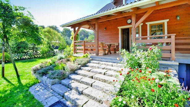 A wooden house with a porch, stone steps, and a garden with flowers. - Holiday Home by the Lake, Private Garden, Oswino (Chociwel)