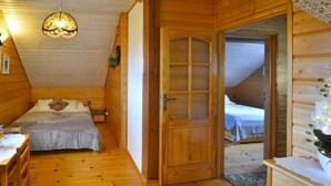 A wooden cabin bedroom with two beds, a wooden dresser, and a ceiling light. - Holiday Home by the Lake, Private Garden, Oswino (Chociwel)