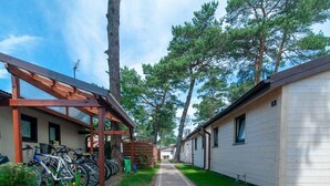 A row of cabins with a covered bike parking area and a paved walkway. - Holiday Cottages, Sauna, Whirlpool, Mrzezyno (Trzebiatow)