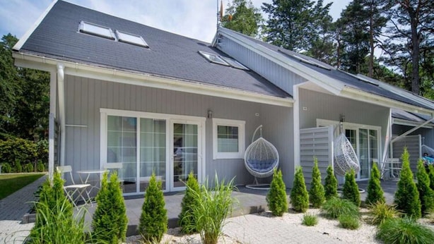 Une maison moderne avec une façade grise, de grandes fenêtres et un patio couvert.