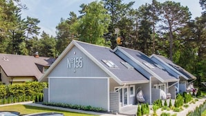 Une rangée de maisons modernes de plain-pied, toutes conçues dans le même style, et numérotées à partir de 155, chacune dotée d’un porche et de panneaux solaires.