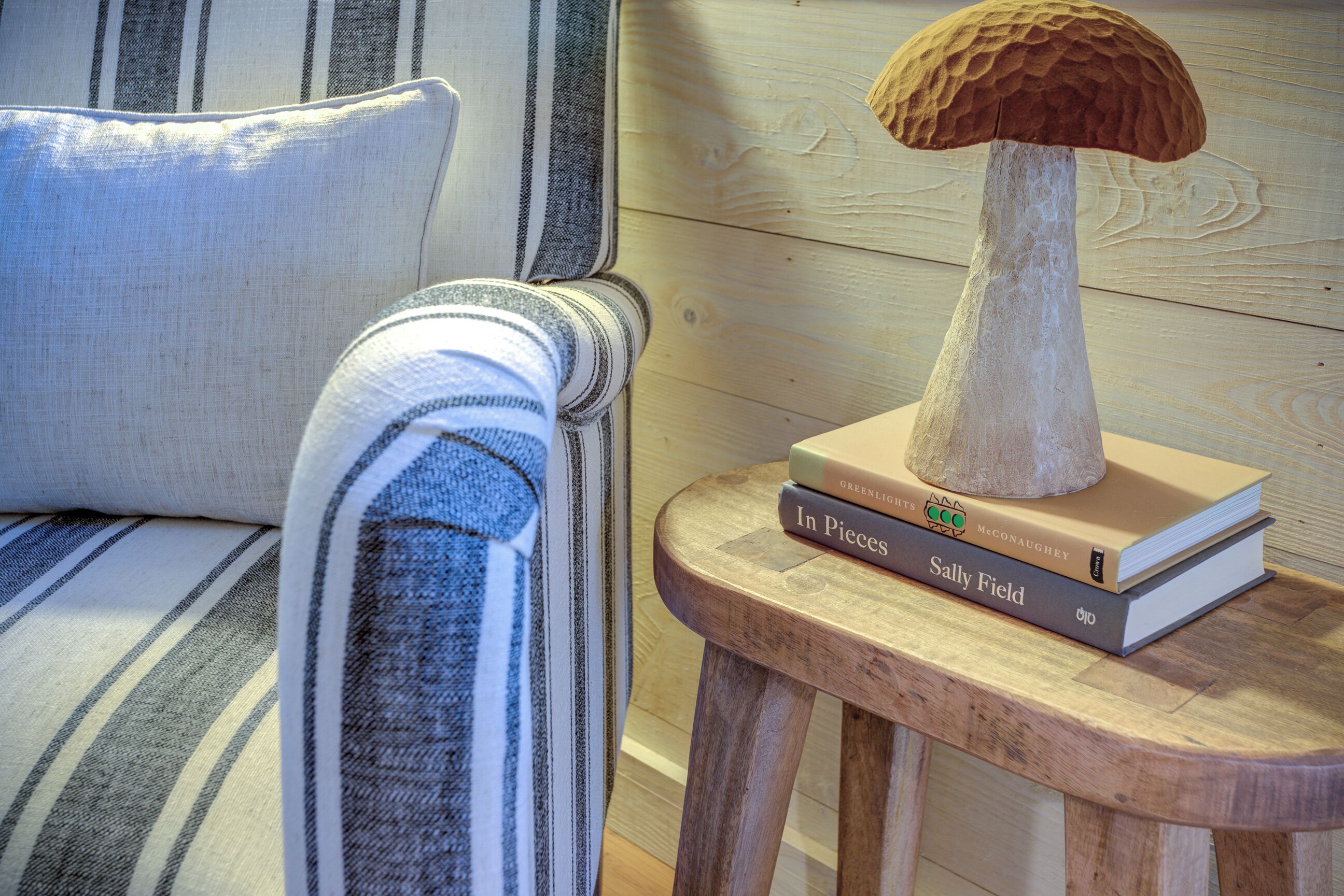 Uno sgabello di legno con una scultura a fungo e tre libri.