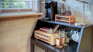 Una cocina con armarios de madera, una cafetera, un molinillo de café y una ventana con persianas.