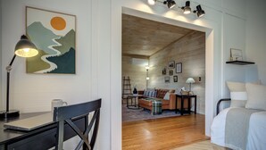 Una sala de estar moderna con techo de madera, un sofá, una mesa de centro y un escritorio con una computadora portátil.