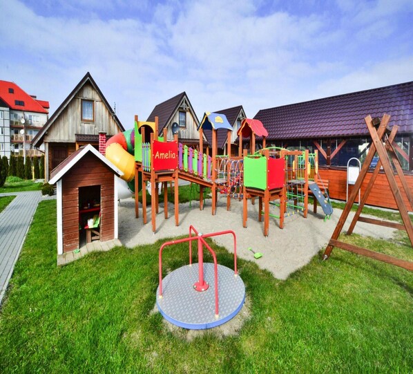 Ein Spielplatz mit Rutsche, Klettergerüsten und einem kleinen Häuschen mit dem Namen Amelia.