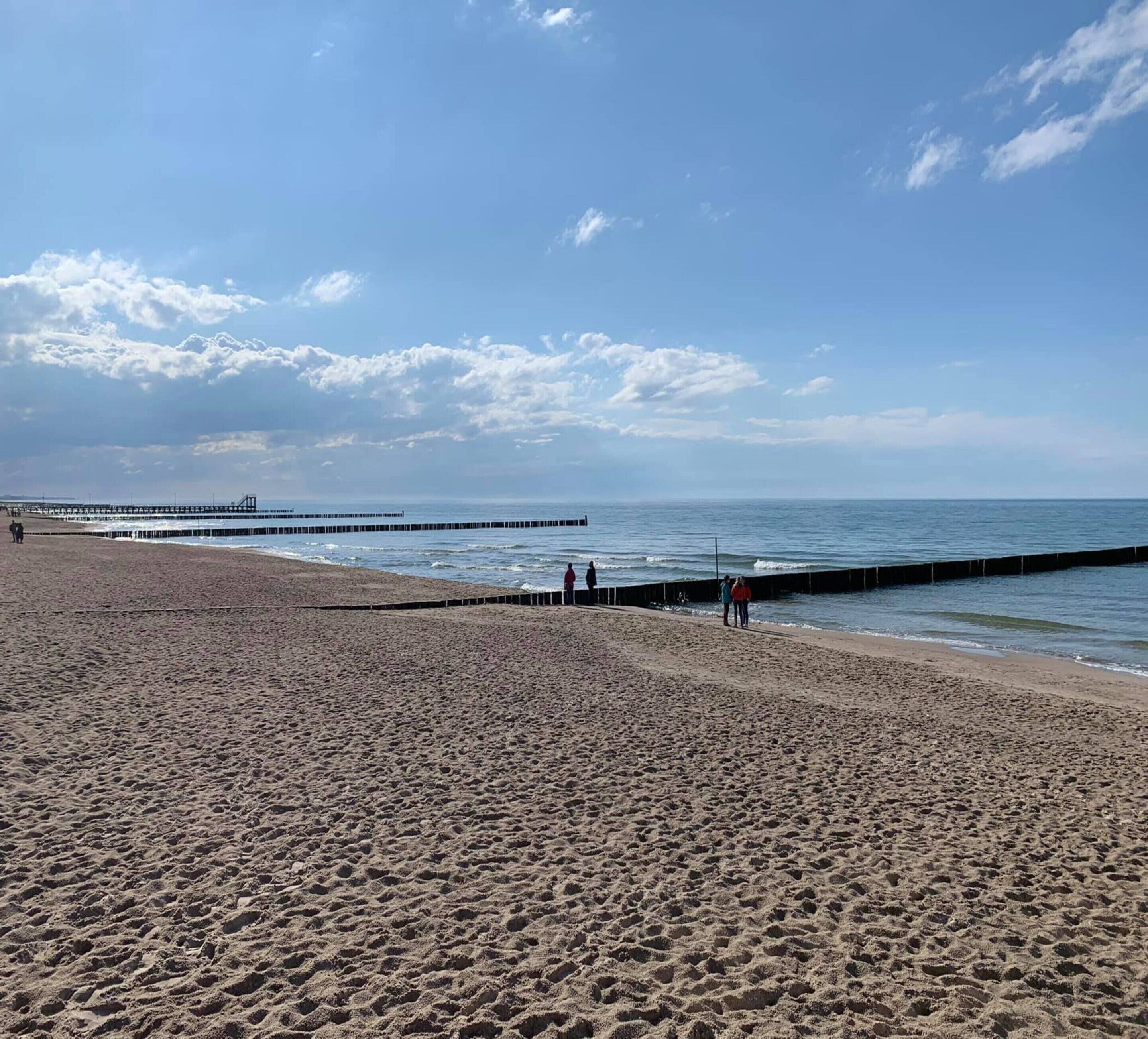 A sandy beach with a pier extending into the water.