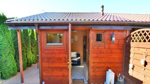 Une cabane en bois avec un toit recouvert de tuiles, une porte donnant sur l’intérieur et une petite fenêtre.