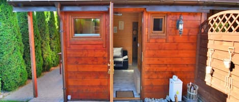 A wooden cabin with a tiled roof, a door leading inside, and a small window.