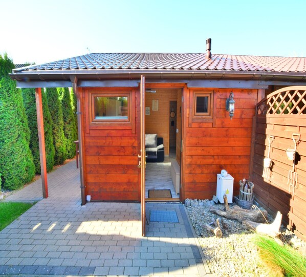 Une cabane en bois avec un toit recouvert de tuiles, une porte donnant sur l’intérieur et une petite fenêtre.