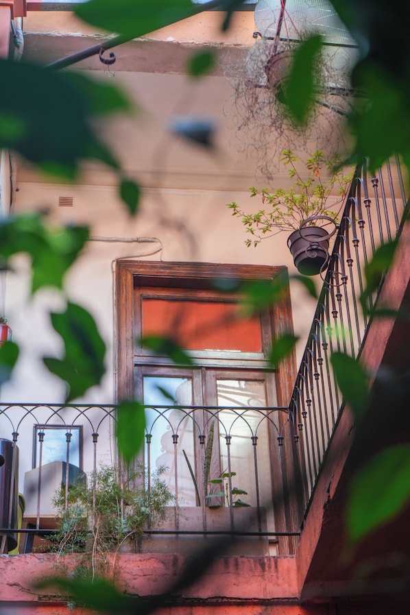 A balcony with a wooden door, a metal railing, and potted plants. - ViaVia BsAs GuestHouse (Buenos Aires)