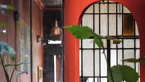 Een hal met potplanten, een rode muur en een raam met een 'SAL'-bord.