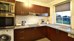 A modern kitchen with dark wooden cabinets, a built-in microwave, oven, and washing machine. - Comfortable Ground Floor Apartment, Summer Pool (Mielno)