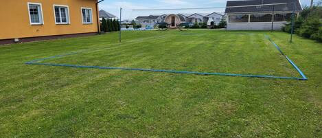 A well-maintained grassy area with a sports field marked by blue lines, surrounded by residential buildings.