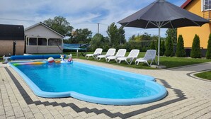 A rectangular swimming pool with a zigzag edge, surrounded by white lounge chairs and a large umbrella. - Comfortable Ground Floor Apartment, Summer Pool (Mielno)
