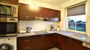 Una cucina moderna con elettrodomestici in acciaio inossidabile, pensili in legno e un'ampia finestra.