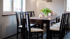A dining area with a rectangular table surrounded by chairs with cushioned seats. - Comfortable Ground Floor Apartment, Summer Pool (Mielno)