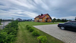 A residential property with a paved driveway, a lawn, and a parked car. - Comfortable Ground Floor Apartment, Summer Pool (Mielno)