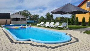 A swimming pool with a unique shape, surrounded by lounge chairs and a covered area. - Comfortable Ground Floor Apartment, Summer Pool (Mielno)