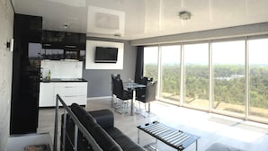 A modern living space with a kitchen, dining area, and large windows offering a view of the outdoors. - Apartment in Dziwnowek Near the Beach (Dziwnów)
