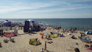 A crowded beach with various tents and beachgoers. - Apartment in Dziwnowek Near the Beach (Dziwnów)