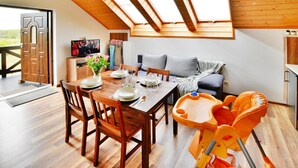 A dining area with a wooden table and chairs, a high ceiling with skylights, and a view of the outdoors. - Comfortable Holiday Apartment, air Conditioning (Ustronie Morskie)