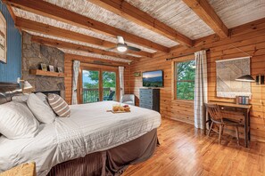 Une chambre dans un chalet en bois, comprenant un lit, un bureau, une chaise et un téléviseur.