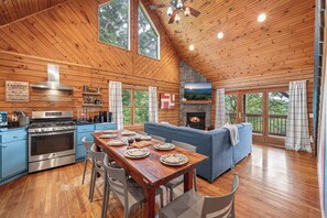 L’intérieur d’un chalet en bois comprend une salle à manger, une cuisine et une cheminée.