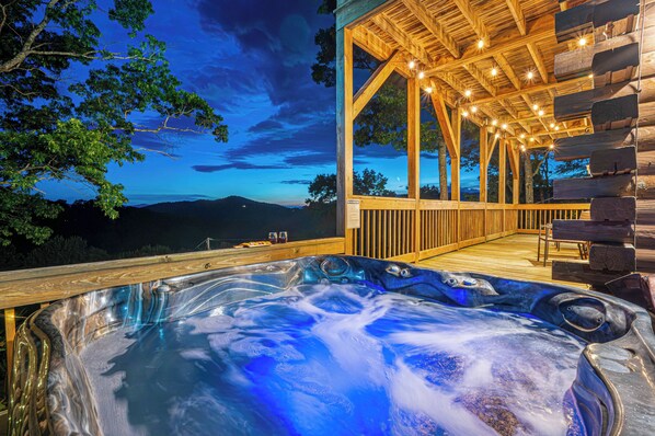 Un bain à remous avec une terrasse en bois et une vue sur les montagnes.