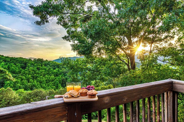 A wooden deck with a breakfast tray containing pastries, juice, and fruit.