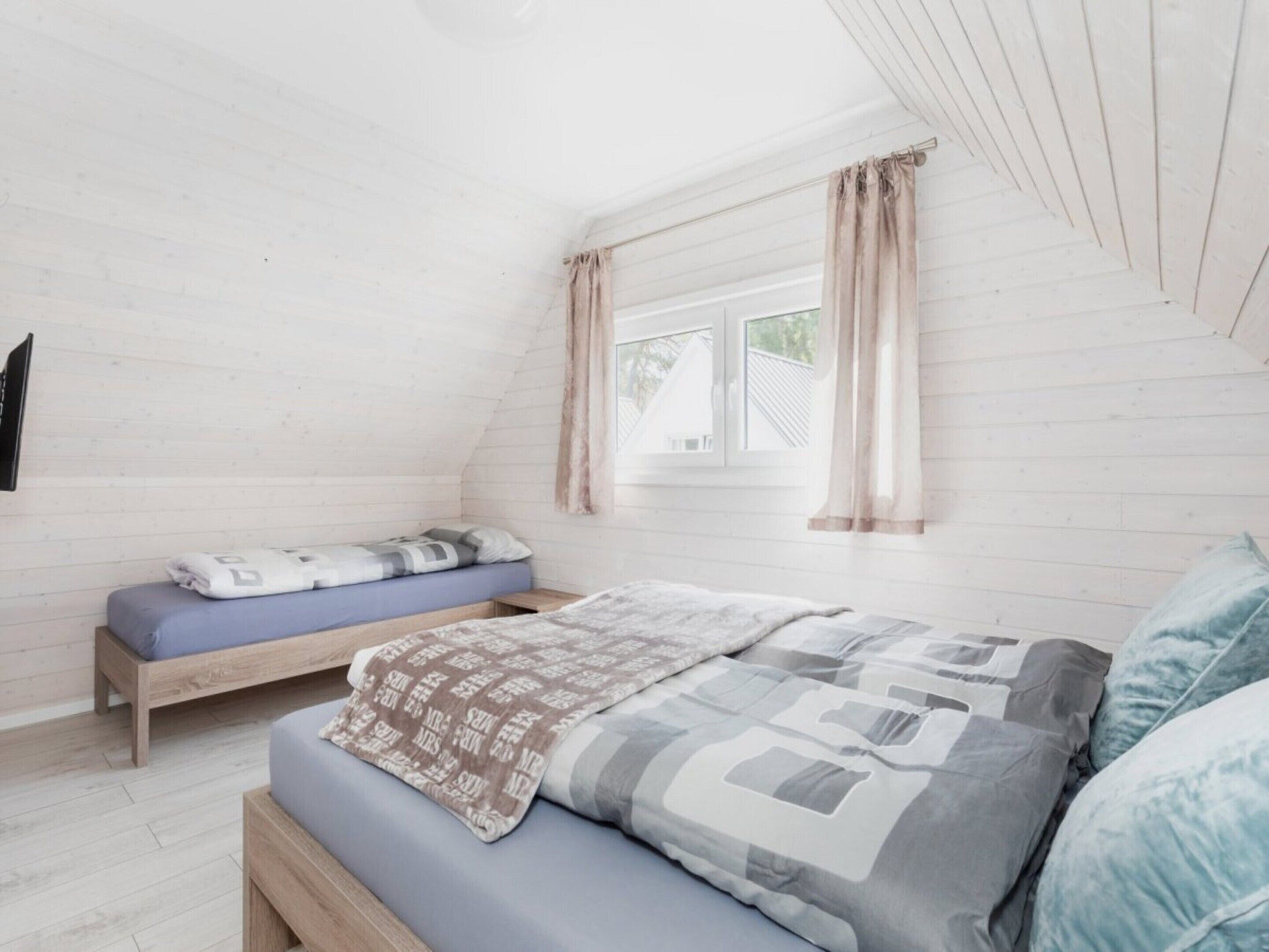 A bedroom with a loft bed, a window with curtains, and a wooden slat ceiling.