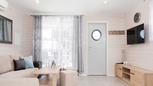 A modern, minimalist living room with a sofa, a coffee table, and a TV mounted on the wall. - Cottage in Pobierowo Near Baltic Beach (Rewal)