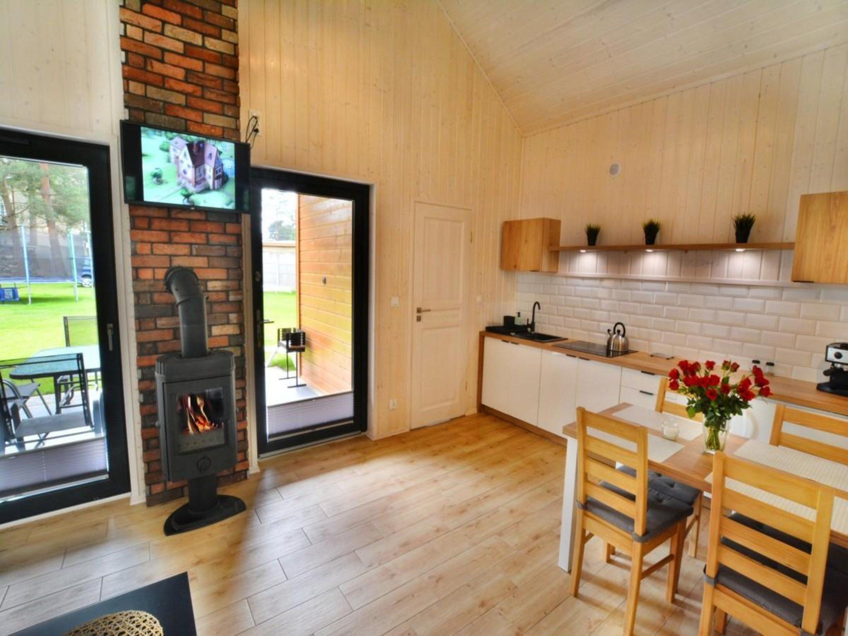 A modern kitchen with wooden cabinets, a built-in stove, and a dining area with a table and chairs.