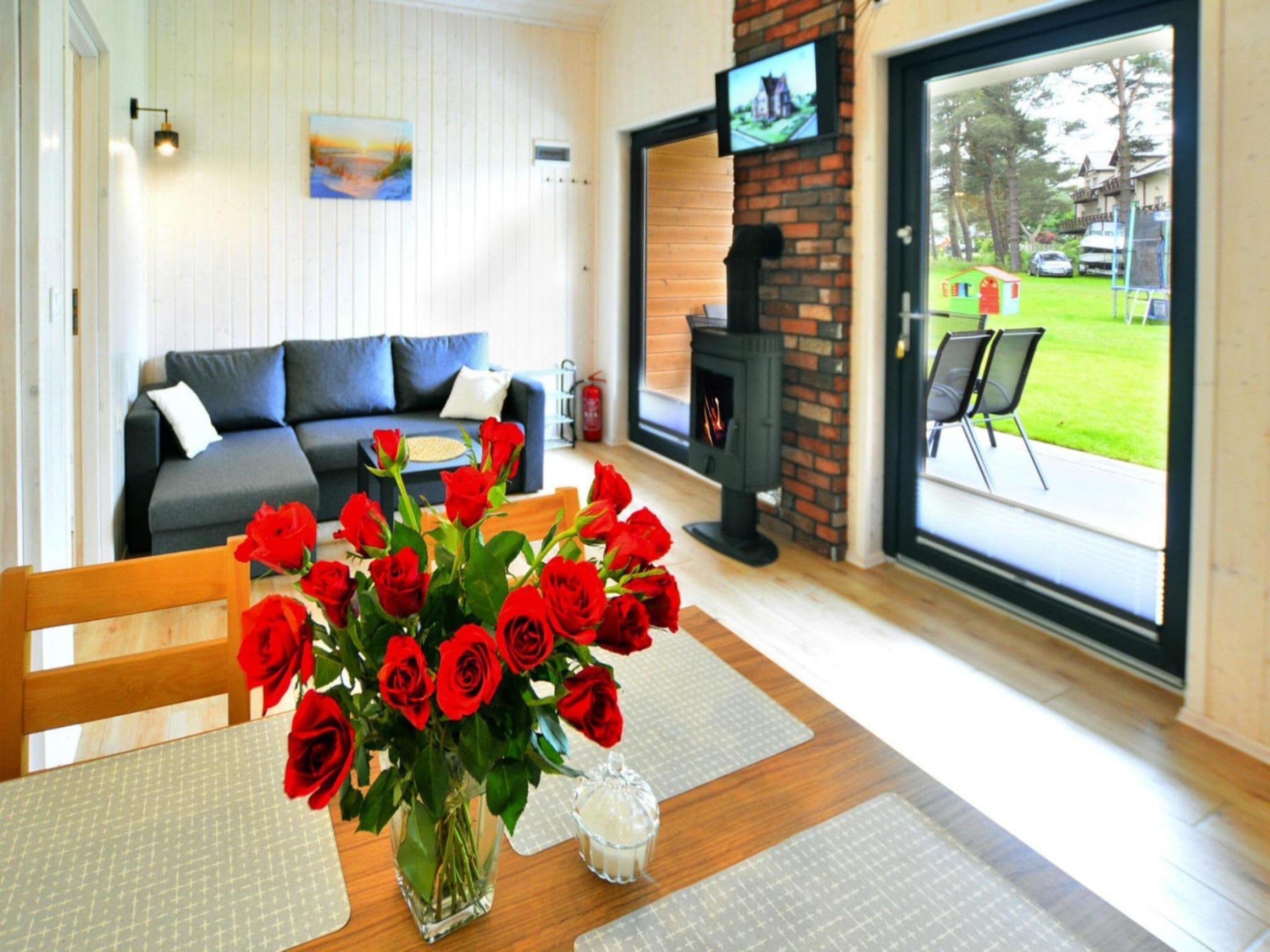 A living room with a sofa, a fireplace, a TV, and a dining area with a table set for two.