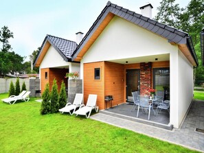 A modern two-story house with a covered patio area, a stone fireplace, and a well-maintained lawn. - Comfortable Holiday Homes, Large Garden (Postomino)