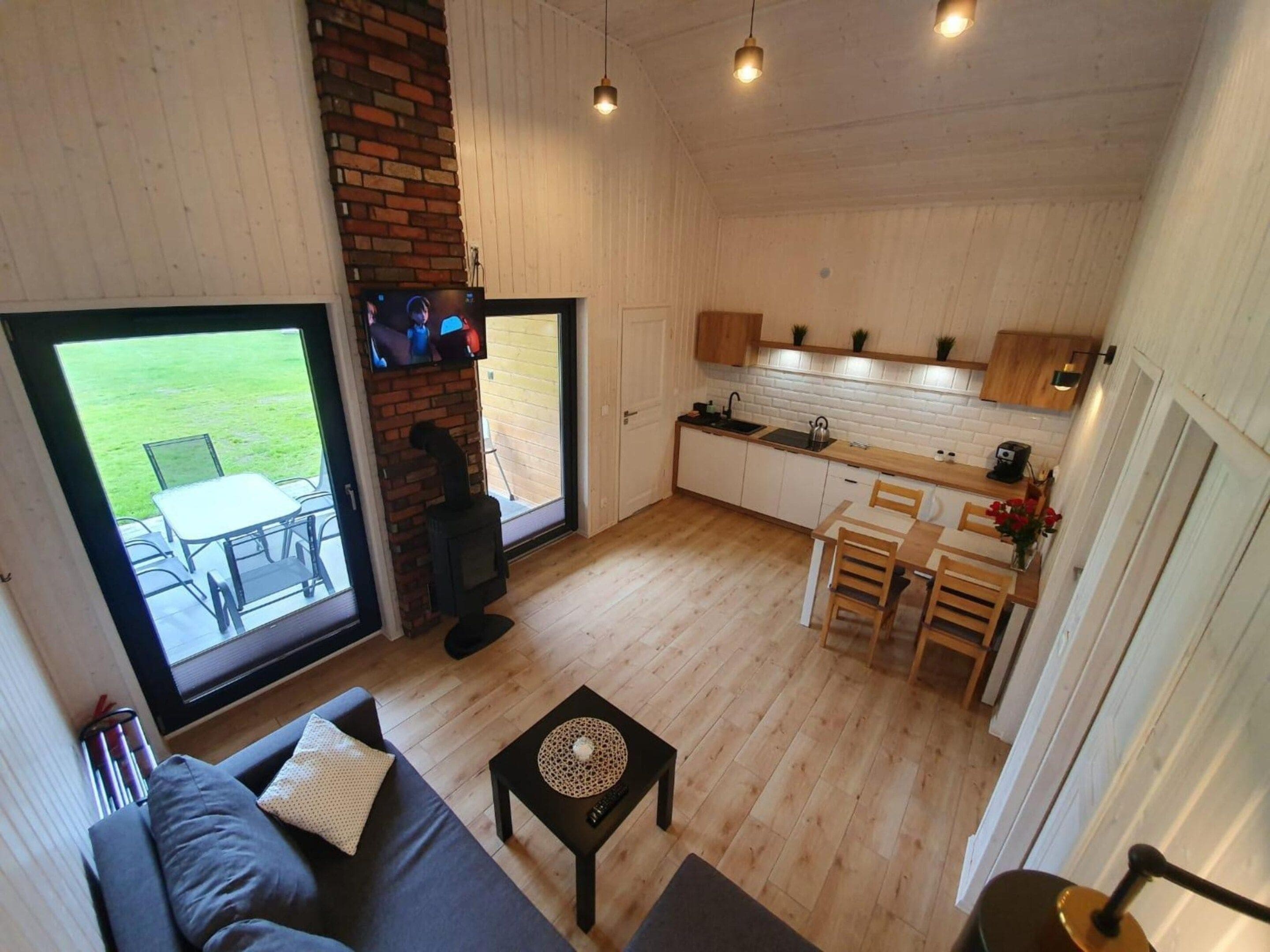 Ein kompakter Wohnraum mit Sofa, kleinem Tisch, einer Küche mit weißen Schränken und einem Kamin.