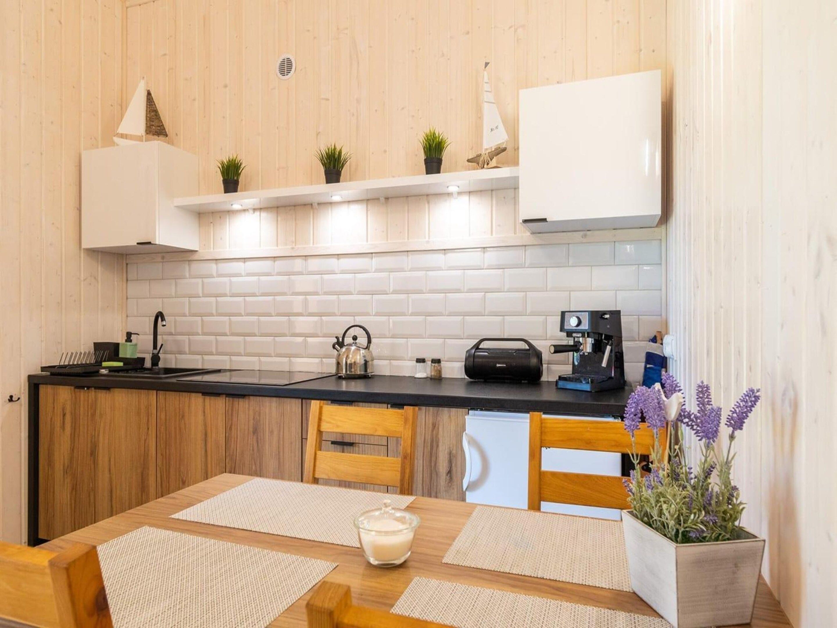 A compact kitchen with a black countertop, white cabinets, and a coffee machine.