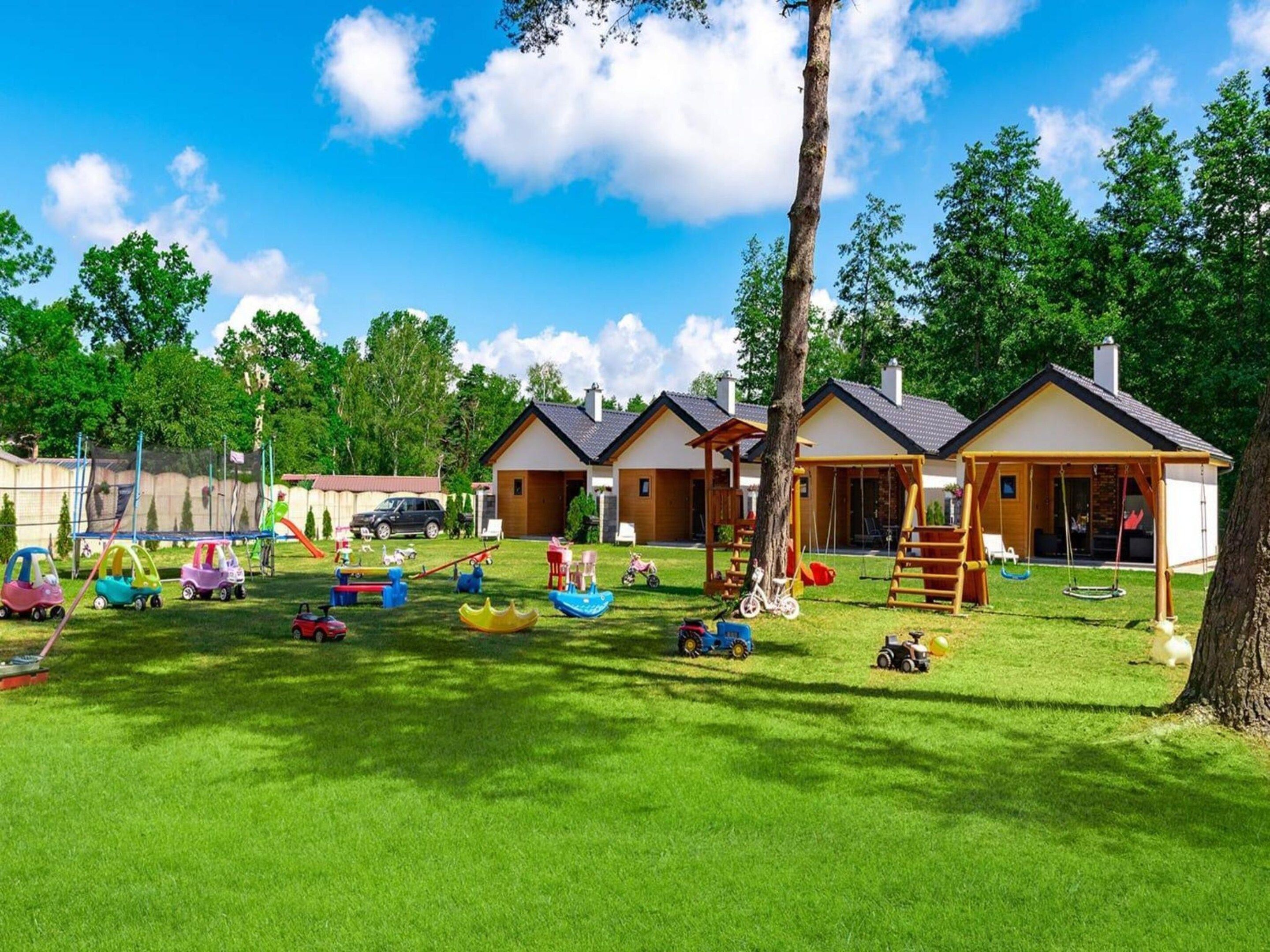 A residential area with multiple houses, a playground with various play equipment, and a clear blue sky.