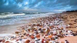 Ein Strand mit felsiger Küste und brechenden Wellen.
