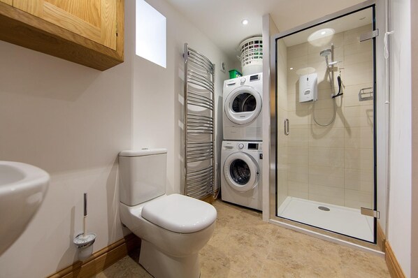 Un baño pequeño con inodoro, lavadora y cabina de ducha.