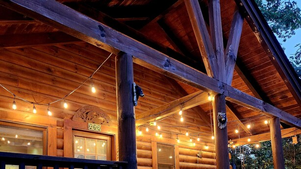A wooden cabin with a porch, string lights, and a rocking chair.