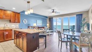 A spacious kitchen with wooden cabinets, a central island, and a dining area with a view of the ocean.