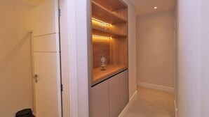 A hallway with a built-in wooden shelf unit, a glass container, and a trash bin. - D055 (Rio de Janeiro)