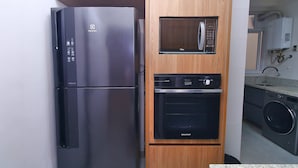 A compact kitchen with a built-in refrigerator, microwave, and oven. - D055 (Rio de Janeiro)
